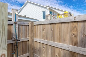 A wooden fence with a gate, a hose, and a house in the background.