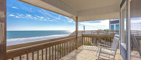 A wooden deck with a view of the beach and ocean.