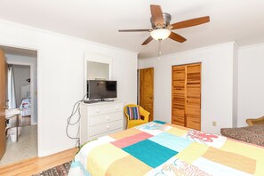 A bedroom with a bed, a television on a dresser, a ceiling fan, and a wooden wardrobe. - Fancy Free - Oceanfront 4 BR. (Surf City)