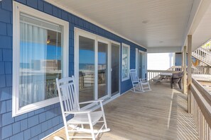 A covered porch with a view of the ocean, wooden deck, and white rocking chairs. - Fancy Free - Oceanfront 4 BR. (Surf City)