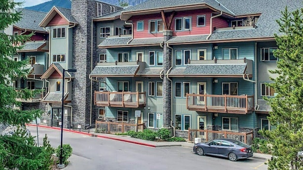 Ein mehrstöckiges Hotel mit Balkonen, einer Steinfassade und einem Blick auf die Berge.
