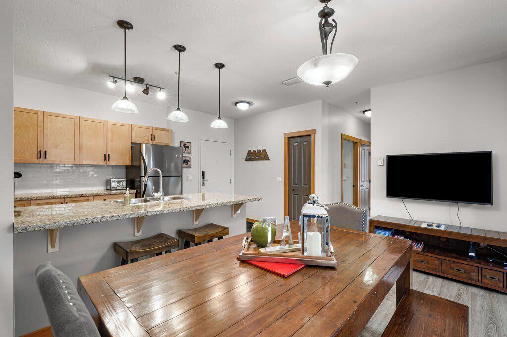 A modern kitchen with wooden cabinets, a granite countertop, and a dining area with a wooden table.