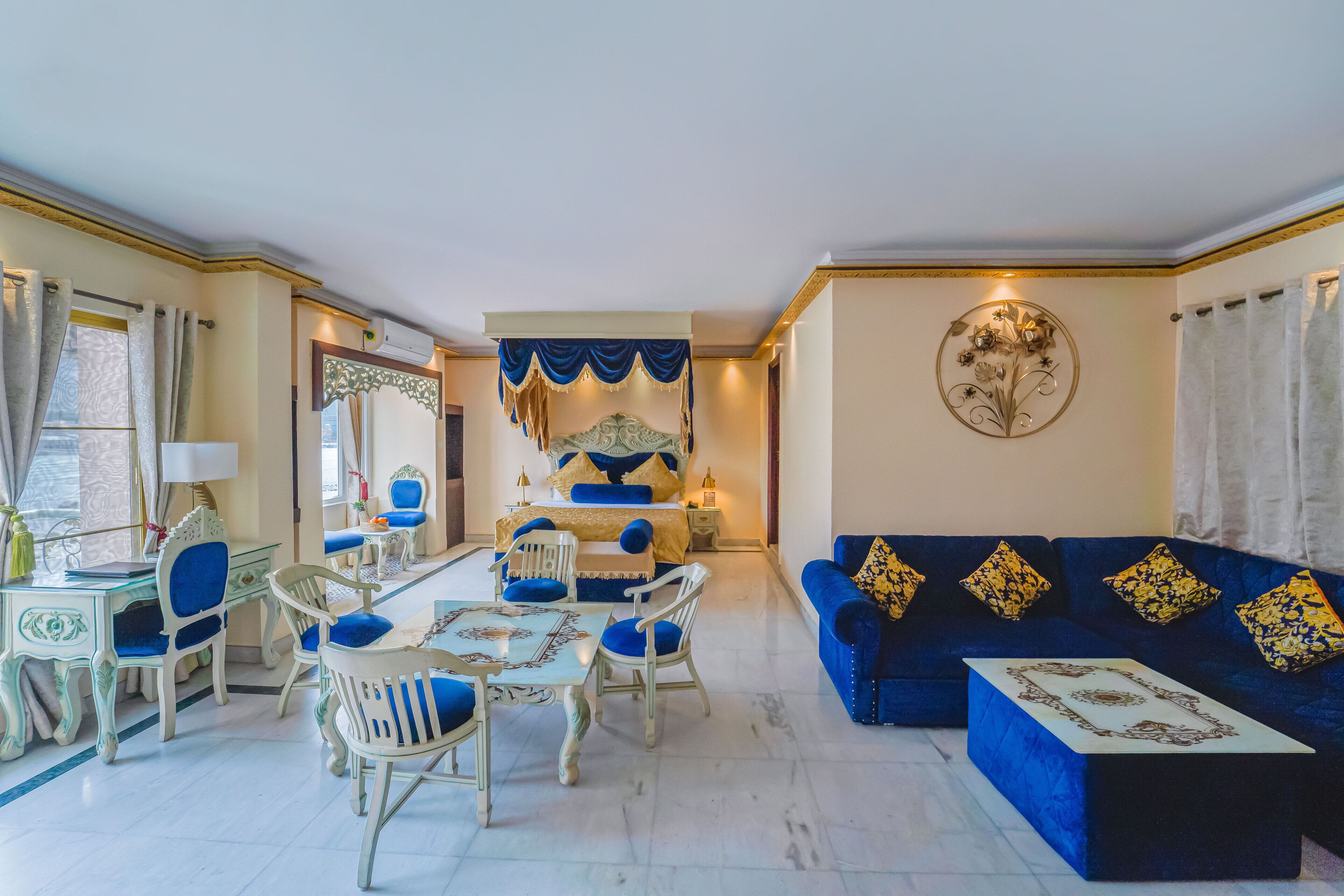 A spacious living room with a blue sofa, a dining table with chairs, and a decorative wall piece.