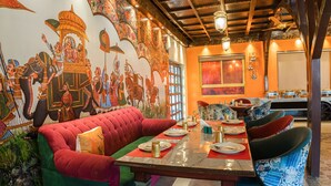Ein Restaurant mit Wandgemälde, roten und grünen Sitzgelegenheiten und einer Holzzieldecke.