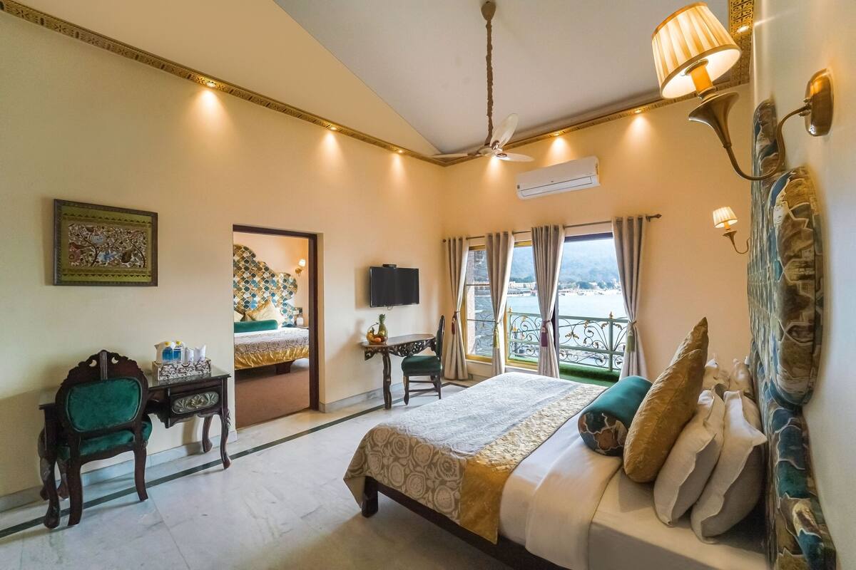 A hotel room with a bed, a desk, a chair, a television, and a balcony with curtains.