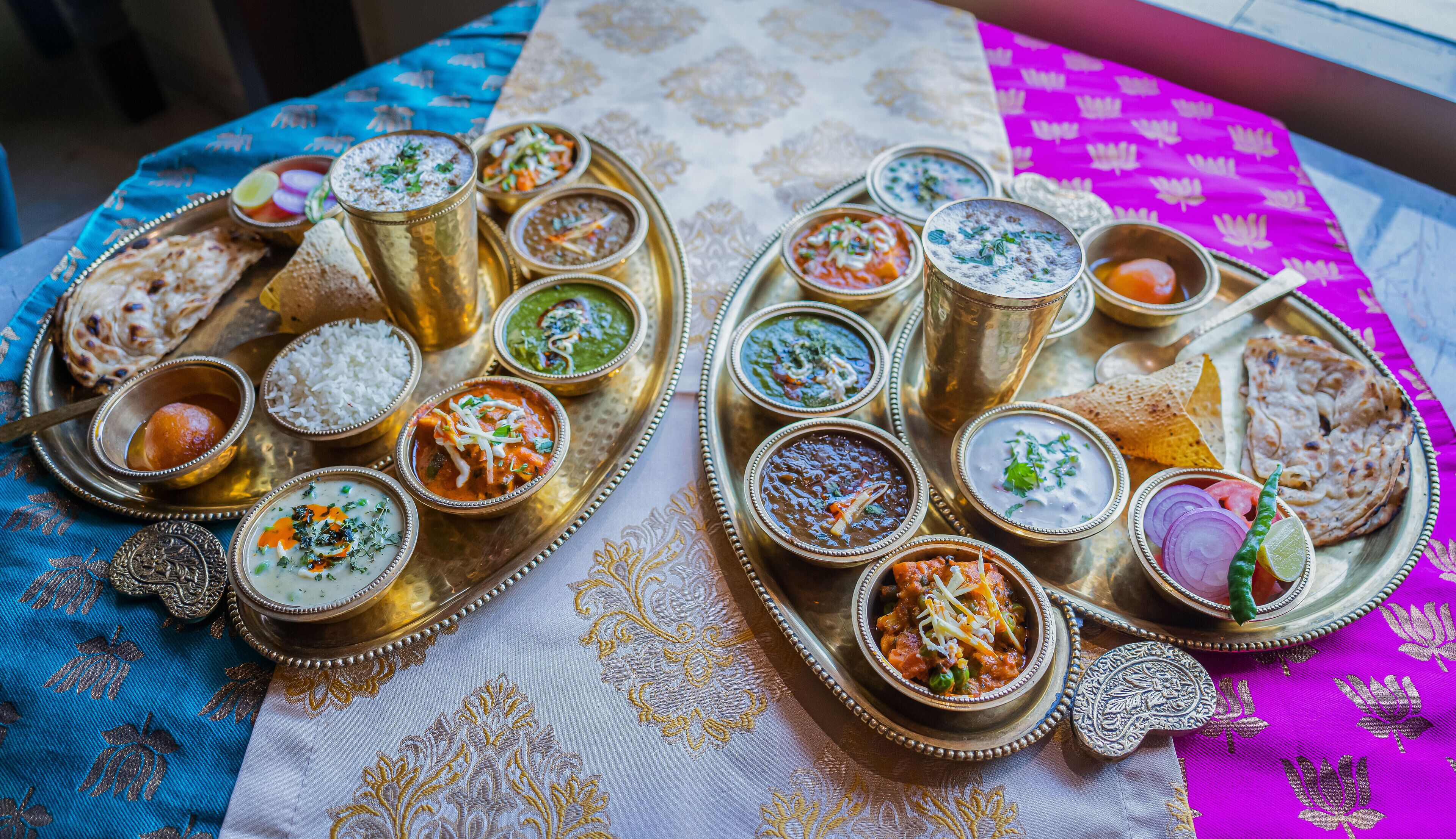 A table with various Indian dishes and a decorative cloth.