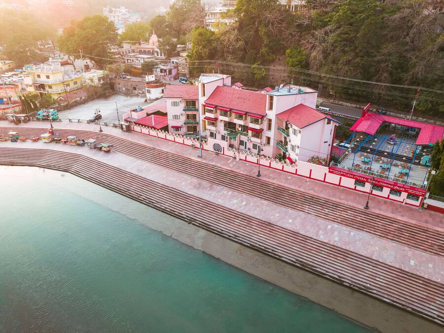 A riverside hotel with a red-roofed building, a swimming pool, and a view of the river.