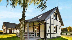 Une maison traditionnelle à colombages, avec un toit en pente, un porche et une porte bien visible.