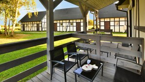 Un espace extérieur aménagé, abrité et doté de bancs et de tables en bois, qui offre une vue sur une cour intérieure bordée de bâtiments traditionnels.