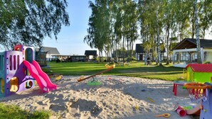 Une aire de jeux avec une balançoire, un toboggan et un bac à sable.