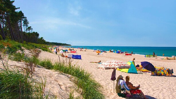 Une plage avec des tentes, des parasols et des gens qui se détendent.