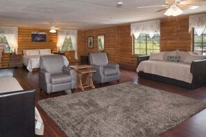 A log cabin-style room with a bed, two armchairs, a small table, and a rug.