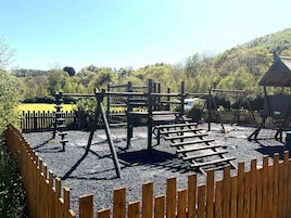 A playground with various climbing structures and a wooden fence surrounding it.