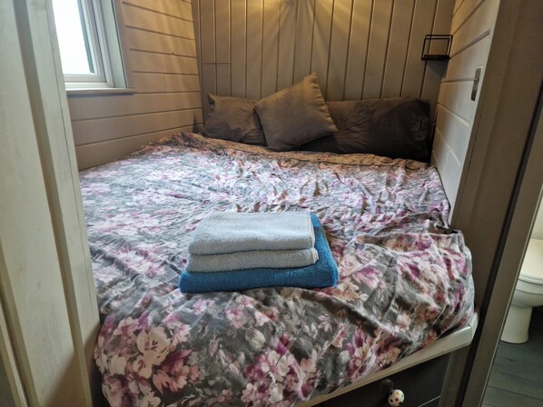 A small, cozy room with a bed, a window, and a toilet. - Glan yr Afon Dau - Relax, Recuperate, Hot Tub (Welshpool)