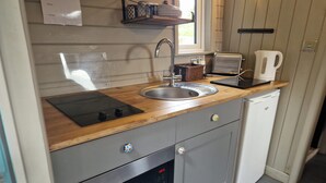 A compact kitchen with a wooden countertop, stainless steel sink, and a built-in oven. - Glan yr Afon Dau - Relax, Recuperate, Hot Tub (Welshpool)