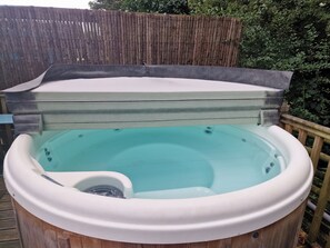 Relax in a hot tub surrounded by lush greenery.