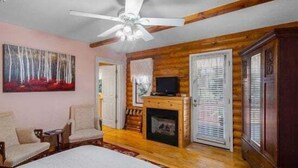 A log cabin-style room with a fireplace, a ceiling fan, and a painting on the wall. - Quarter Horse Inn - Heather Room | Historic Inn | Fireplace | Walk to Downtown & Rail Station (Flagstaff)