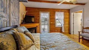 A log cabin bedroom with a bed, a television, and a fireplace. - Quarter Horse Inn - OrchidRoom | Historic Log Inn | Fireplace | Walk to Downtown & Rail Station (Flagstaff)