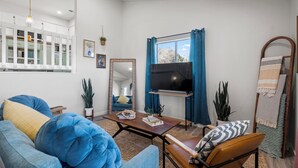 A modern living room with a sofa, armchair, coffee table, and a flat-screen TV mounted on the wall. - The Heritage Hideaway Views Games & More (Leander)