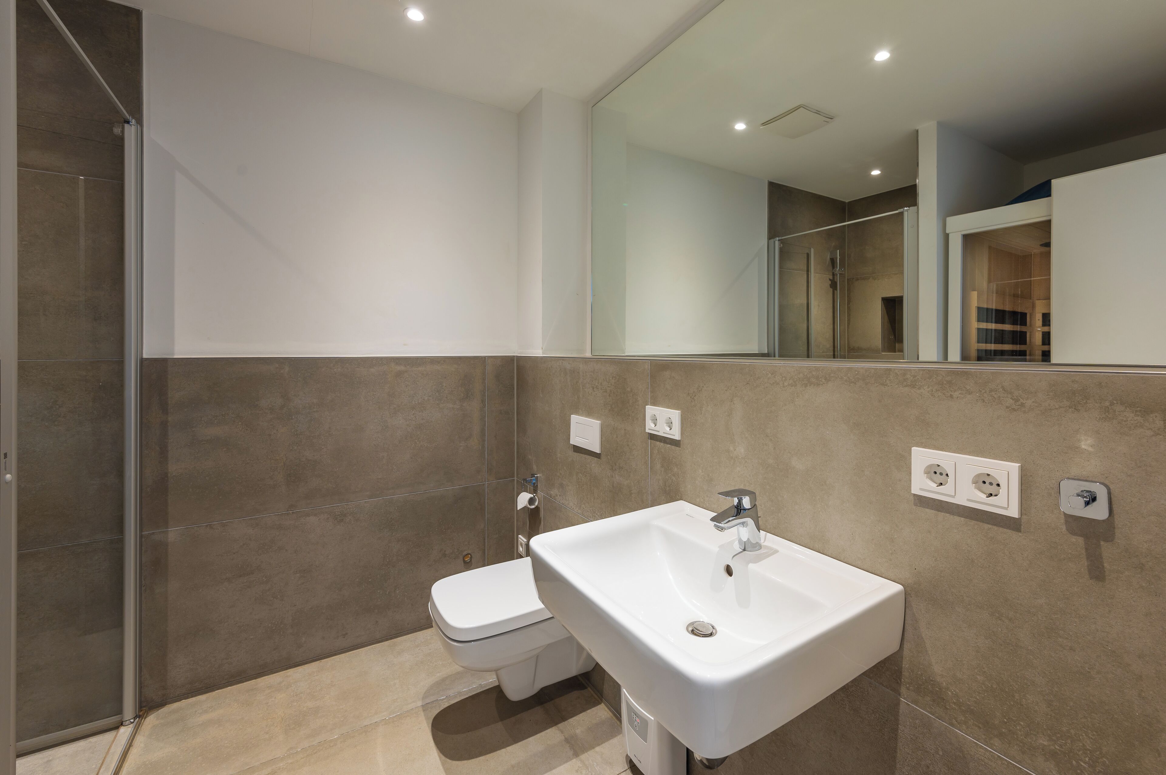 A modern bathroom with a toilet, sink, and shower.
