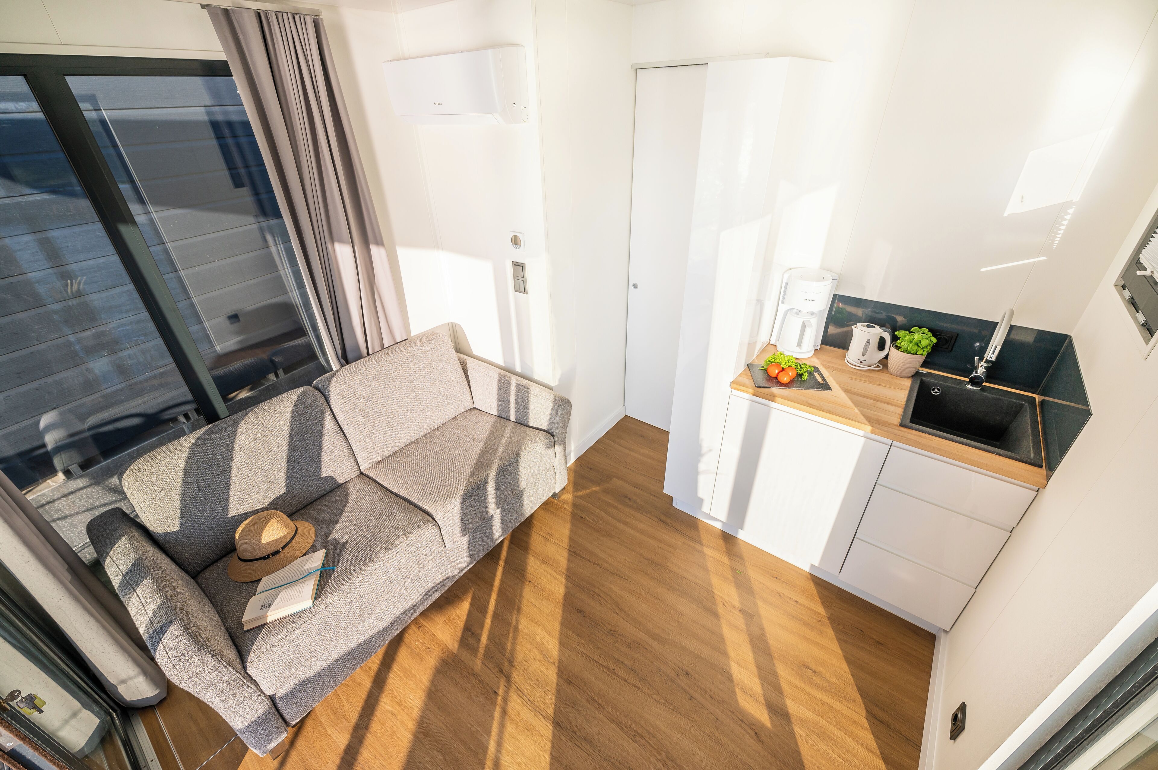 A compact living space with a sofa, a small kitchen area, and a sliding door.