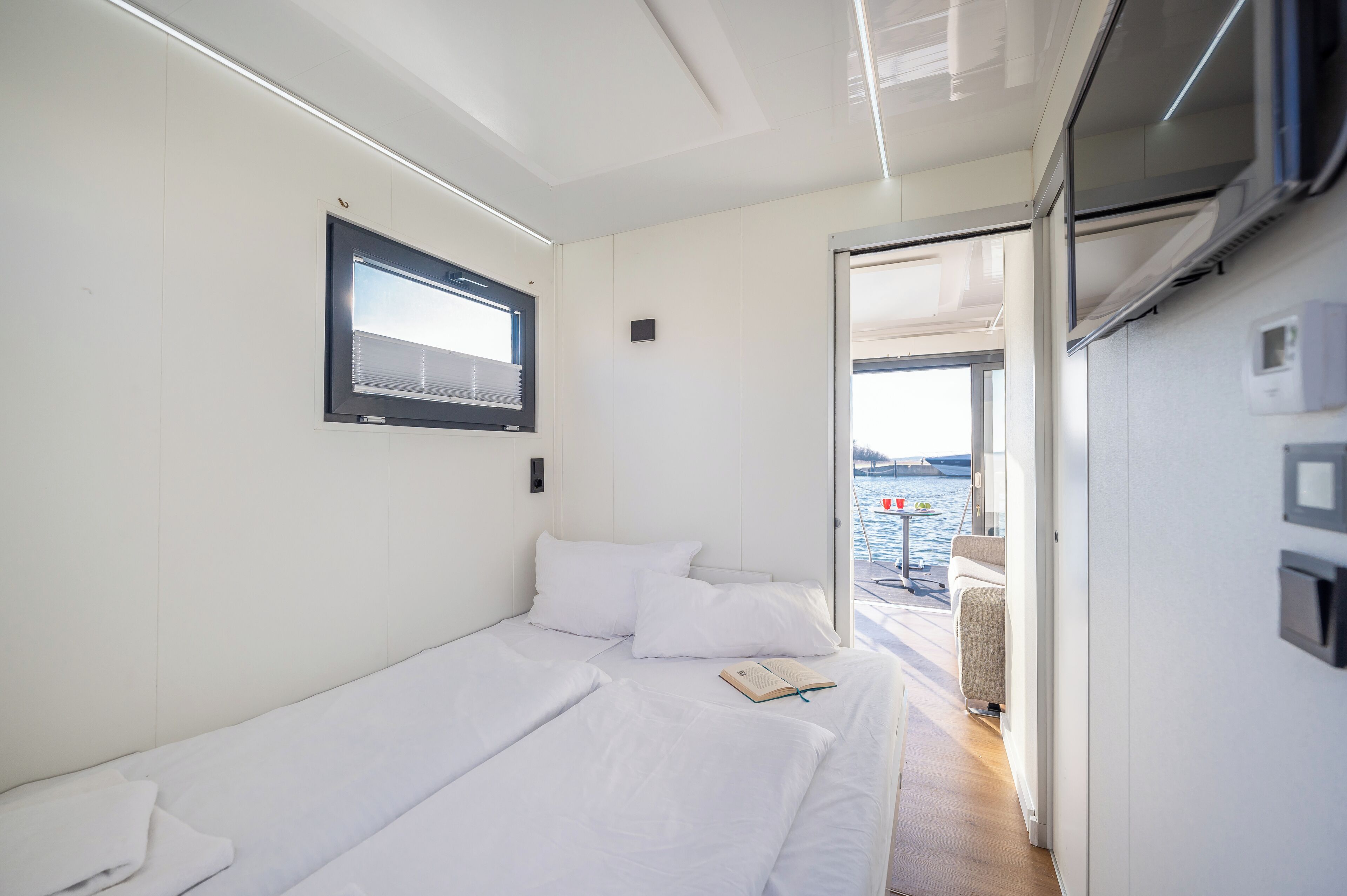 Une chambre moderne et bien éclairée, dotée d’un grand lit, d’une fenêtre et offrant une vue sur la mer.