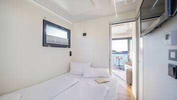 Une chambre moderne et bien éclairée, dotée d’un grand lit, d’une fenêtre et offrant une vue sur la mer.