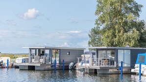 Deux structures flottantes dotées d’espaces de détente en plein air, reliées par un pont et entourées d’eau.