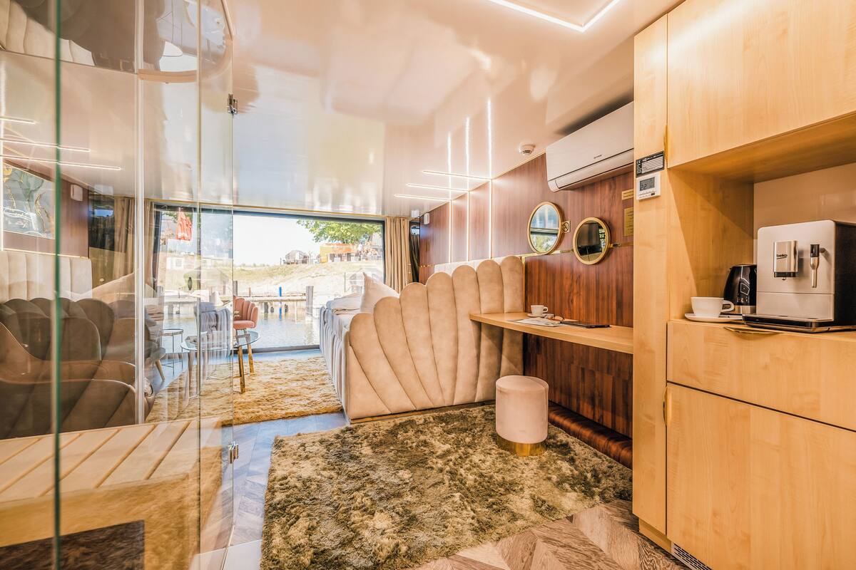 Een moderne hotelkamer met een glazen scheidingswand, comfortabele zithoek, een koffiezetapparaat en uitzicht.