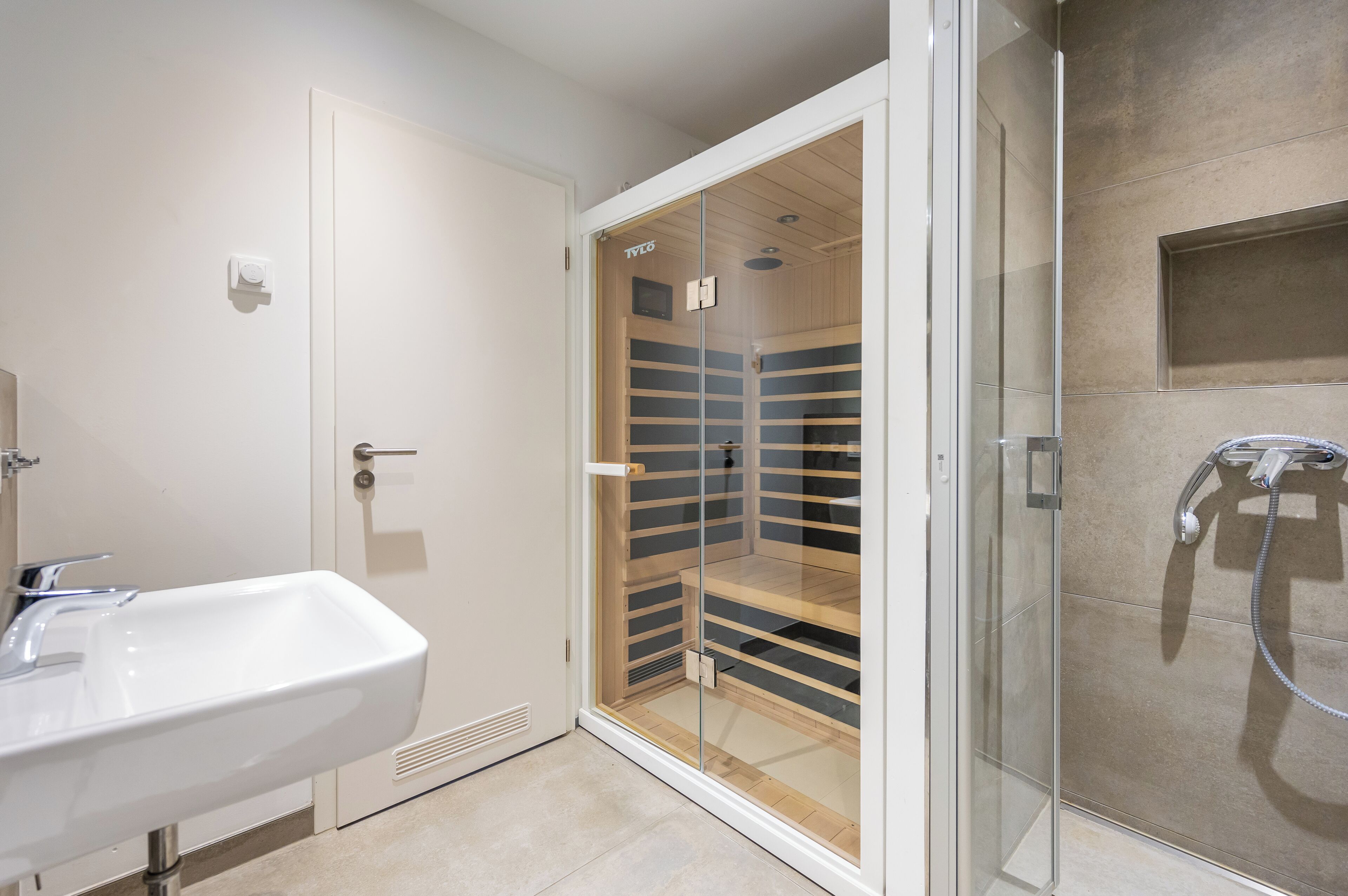 A modern bathroom with a glass-enclosed walk-in closet, a sink, and a shower.