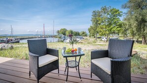 Une terrasse avec deux fauteuils en osier et une petite table sur laquelle on a disposé des fruits et des tasses.