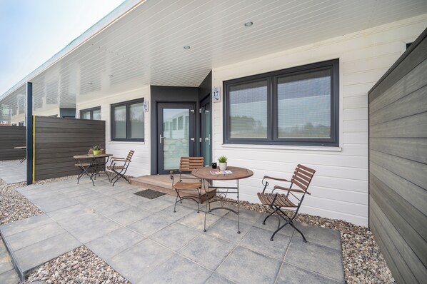 A patio with a table and chairs, a small potted plant, and a door leading to a covered area. - Marina Martinshafen (Sagard)