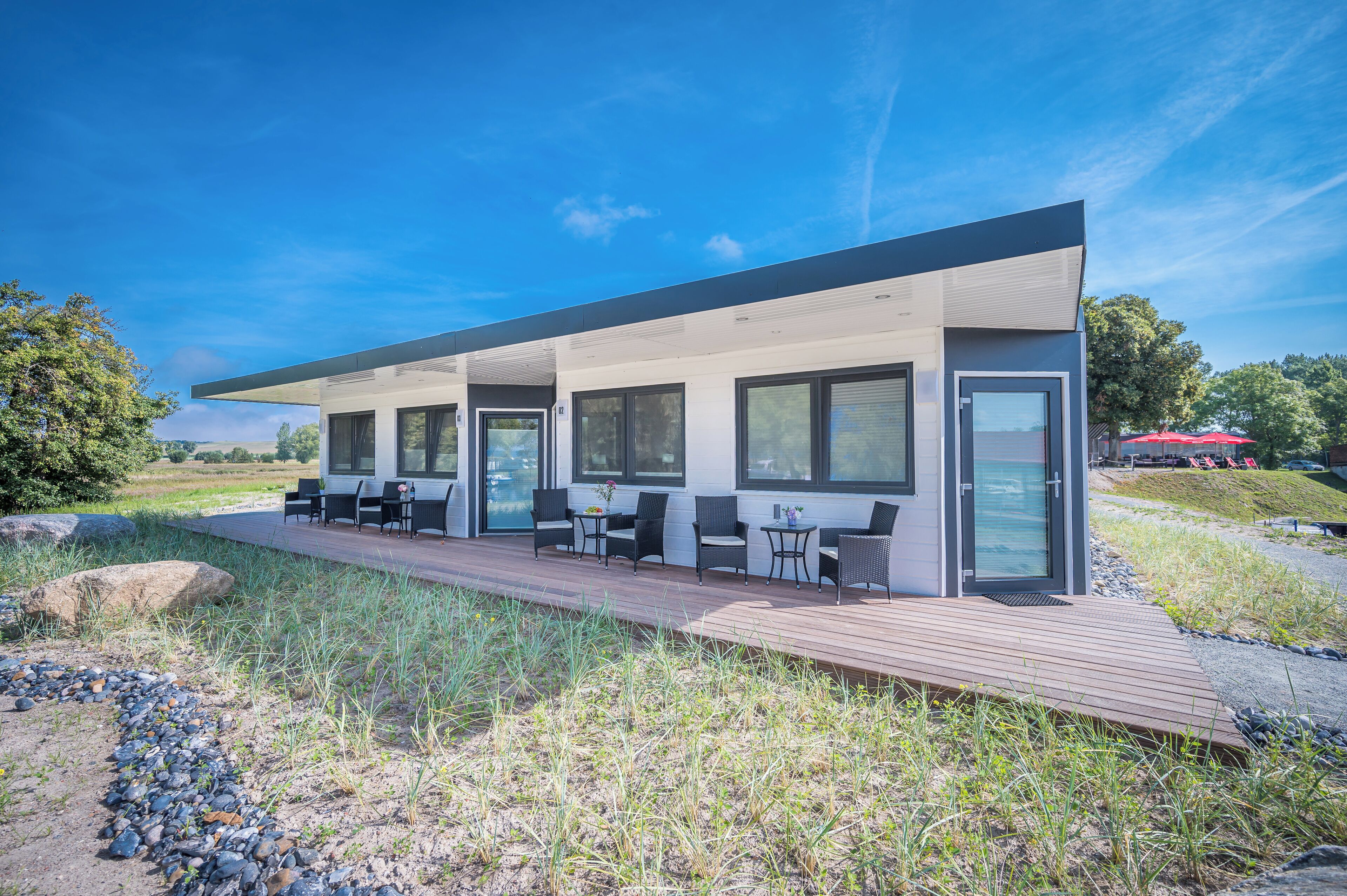 A modern building with a covered outdoor seating area, large windows, and a wooden deck.