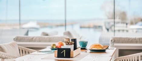 A breakfast setting with a wooden table, a number one sign, a croissant, a bowl, and a cup.