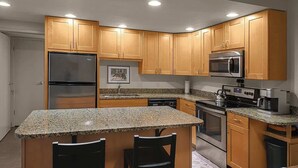 A modern kitchen with wooden cabinets, granite countertops, a stainless steel refrigerator, a microwave, an oven, and a coffee maker. - Rocky Mountain Sanctuary (Steamboat Springs)