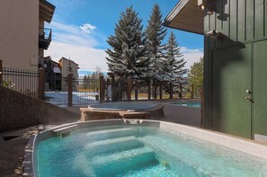 Uma área de hidromassagem com piscina, cercada por uma vedação e árvores.