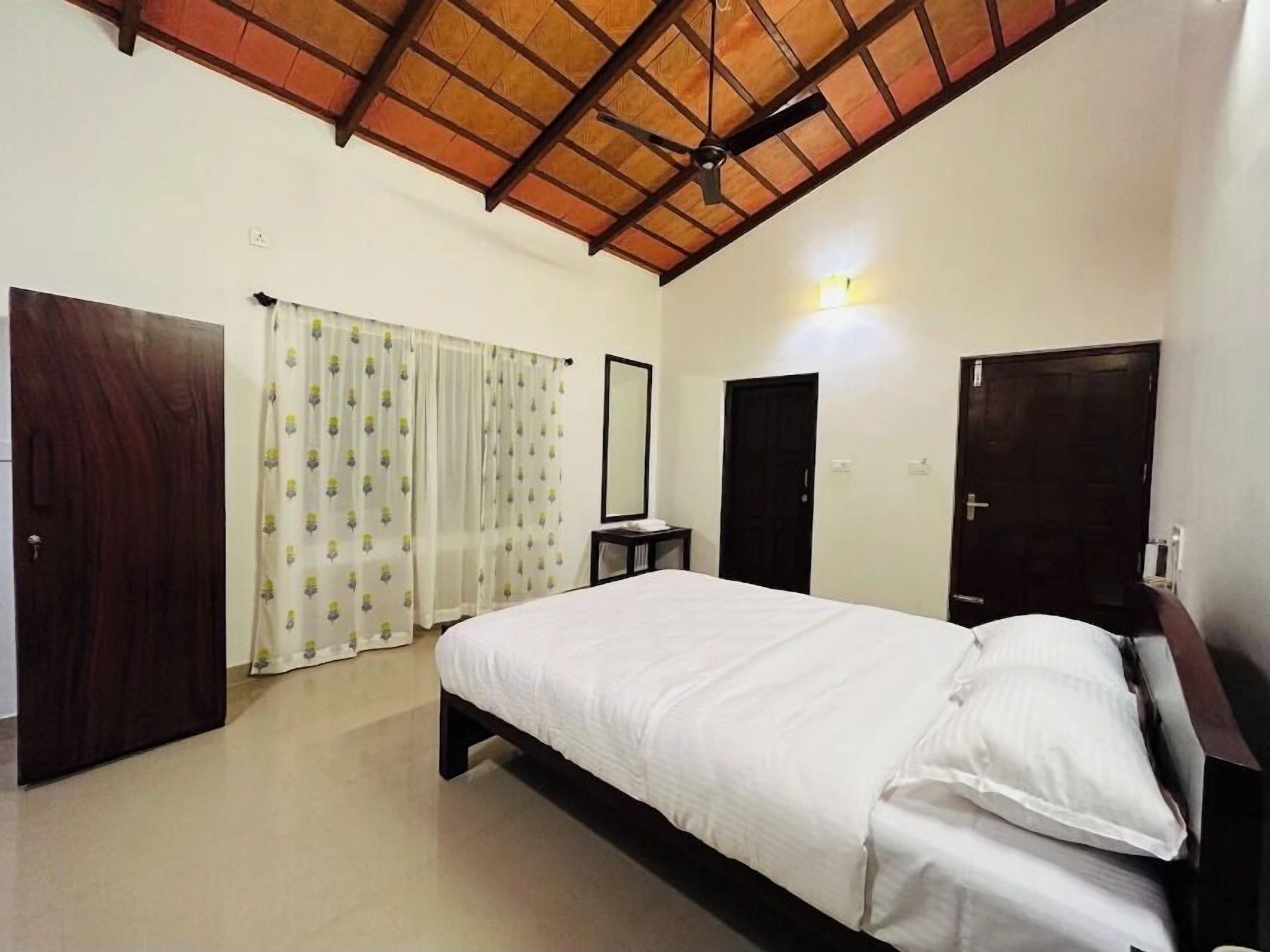 Un dormitorio con cama, ventilador de techo, espejo y puerta.
