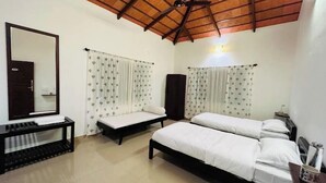 A bedroom with two single beds, a large mirror, a wooden ceiling fan, and a small table with a keyboard. - Villa Mercara (Madikeri)