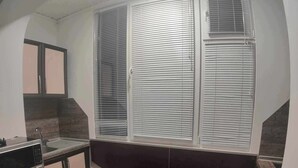 A kitchen with a curved countertop, a built-in microwave, and a window with blinds.