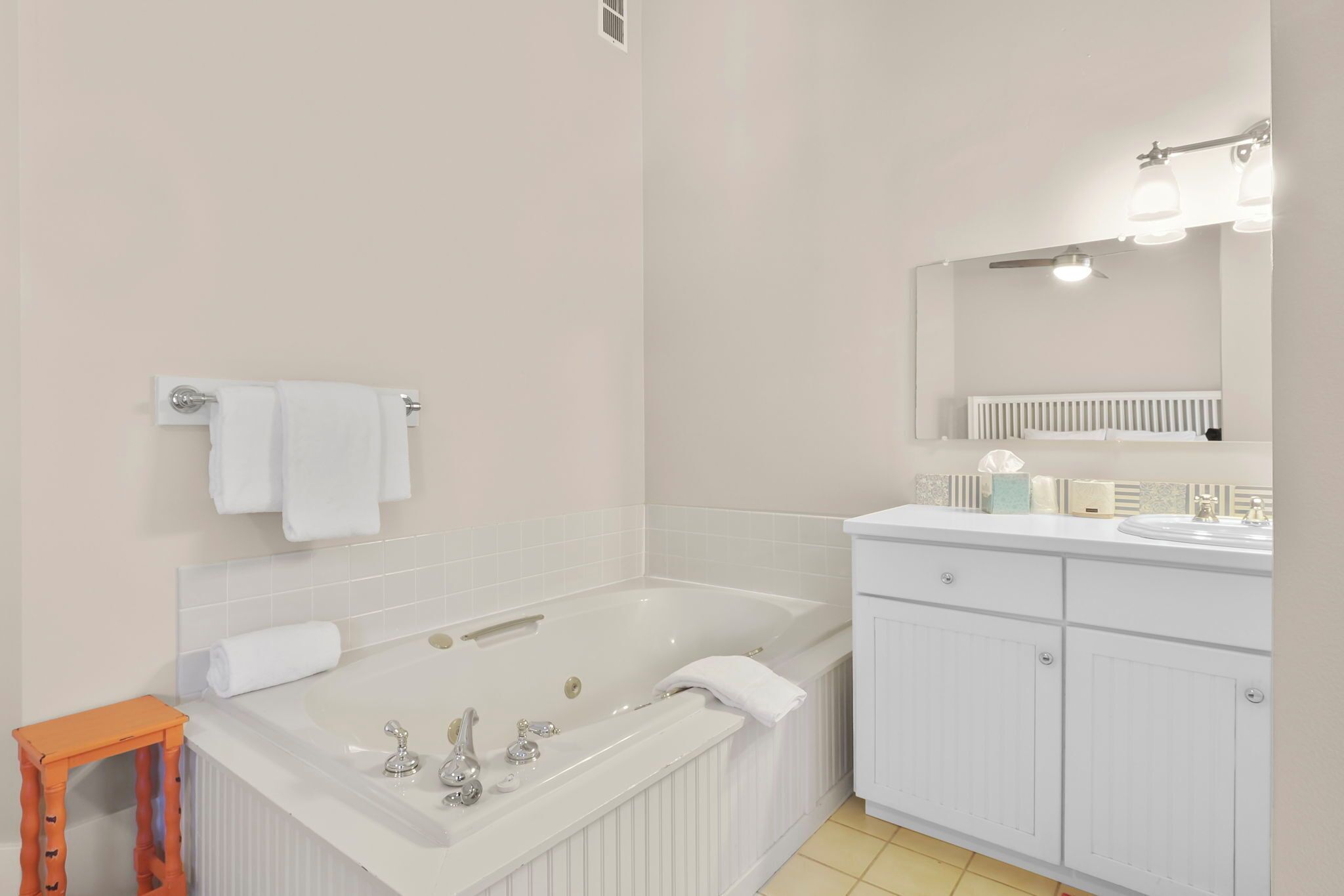 Une salle de bain moderne avec une grande baignoire, des meubles blancs et un miroir avec éclairage intégré.