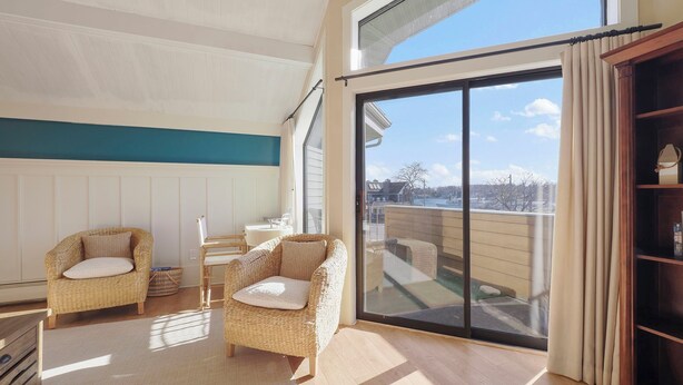 A spacious balcony with a view of the city, furnished with wicker chairs and a small table. - 200 Pointes North | Water View | Downtown Charlevoix | Indoor/Outdoor Pool (Charlevoix)