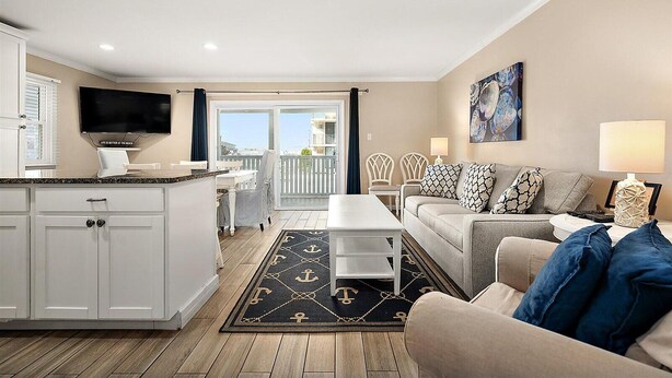 Un salon avec un canapé, une table basse et un téléviseur. Il y a un balcon avec vue.