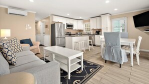 Un appartement moderne comprenant un salon, un coin repas, une cuisine et un téléviseur fixé au mur.