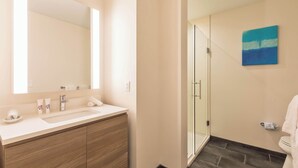 Une salle de bain moderne avec un grand miroir, un lavabo et une douche à parois de verre.