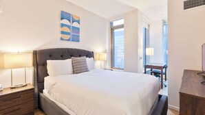 Une chambre à coucher bien aménagée, avec un grand lit, des lampes de chevet, une table de nuit et une œuvre d’art accrochée au mur.