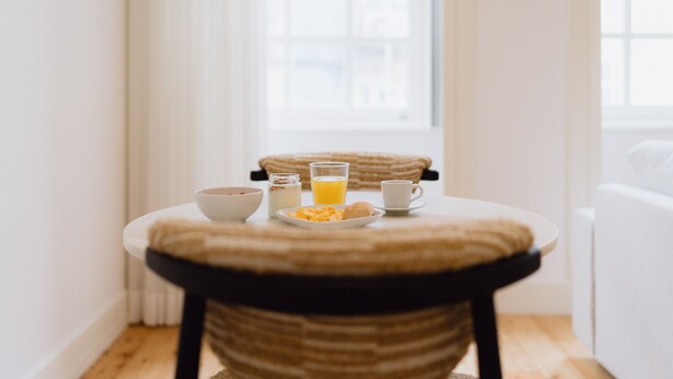 Una mesa de desayuno con un tazón, un vaso de jugo de naranja, una taza y un plato de comida.