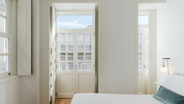 Et soveværelse med en stor seng, et vindue og en dør til en udendørs balkon.