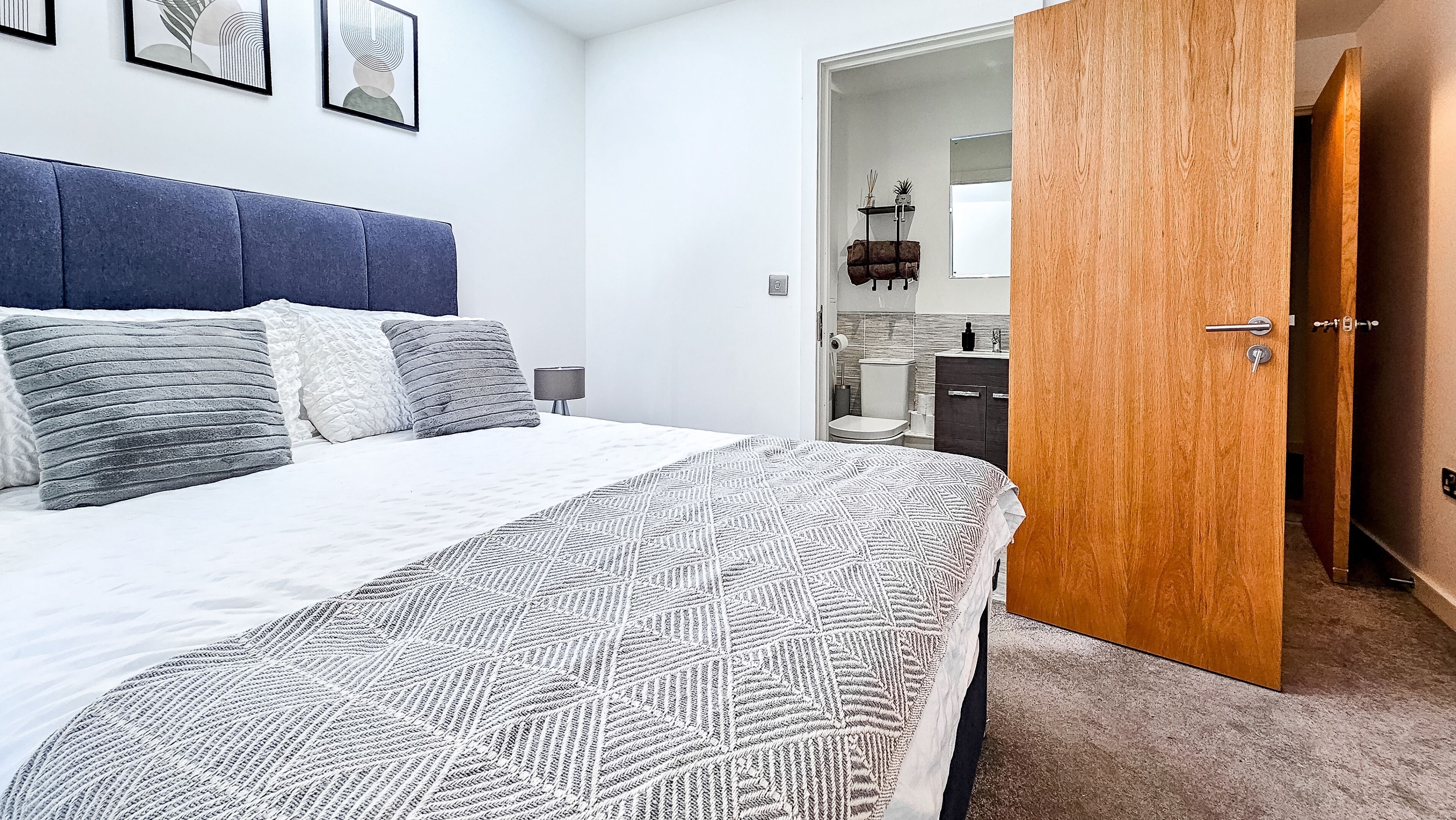 A neatly arranged bedroom with a bed, bedside table, and a wooden door leading to another room.