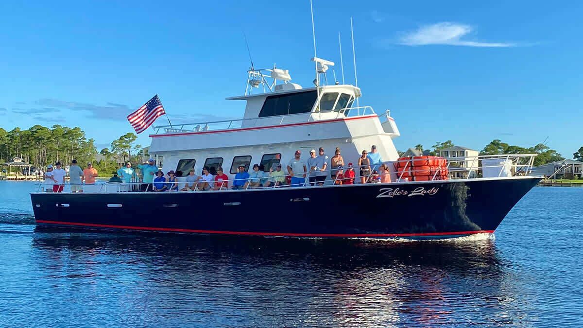 A boat named 'Zelda's Lady' with passengers on board, docked at a marina.
