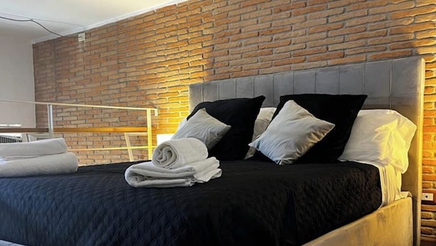 Una habitación de hotel moderna con una cama grande, una pared de ladrillo decorativa y suelo de madera.